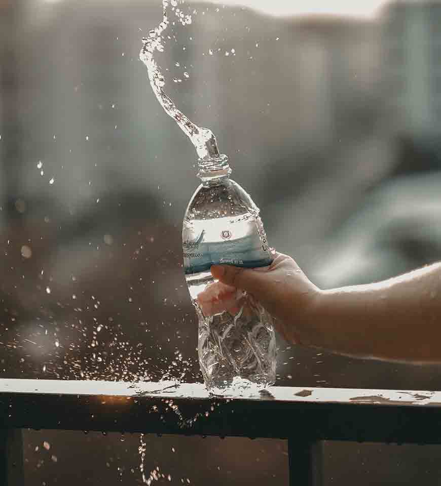 A hand squeezing a plastic water bottle