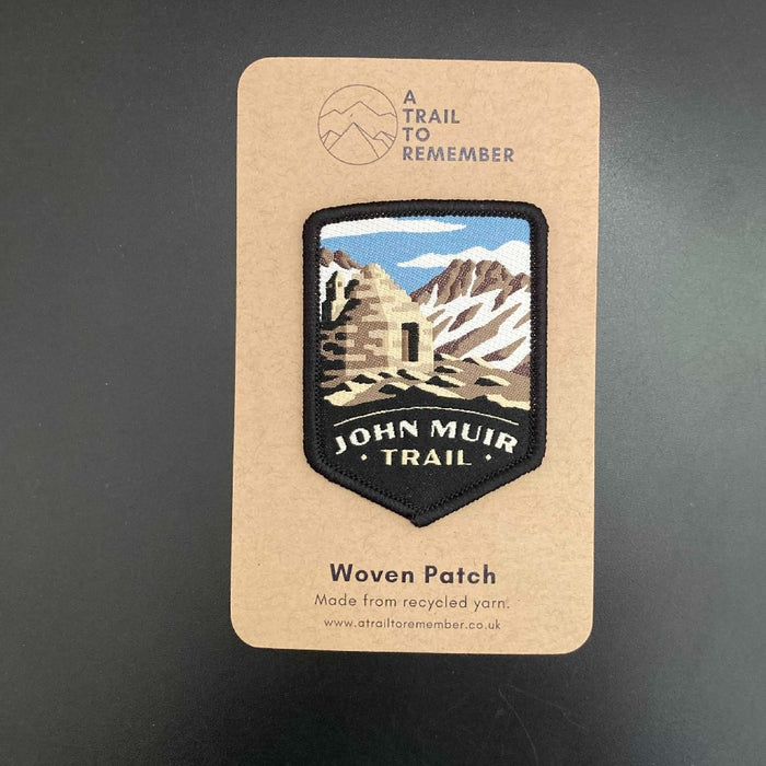 John Muir Trail woven patch on a cardboard backing with 'A Trail to Remember' branding.