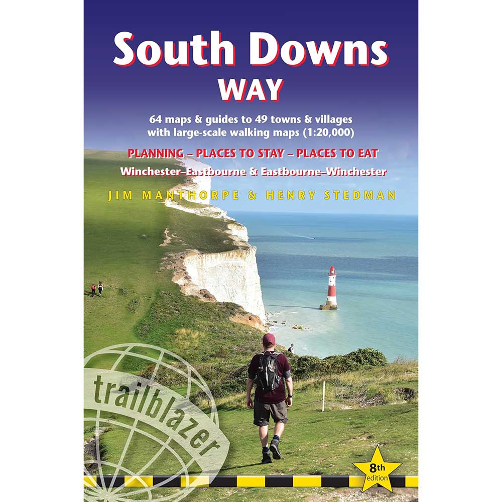 Front cover of the Trailblazer 'South Downs Way' guidebook, featuring a scenic photograph of a hiker on a grassy cliffside overlooking the English Channel with white chalk cliffs and a red-and-white lighthouse. The cover has a blue-to-purple gradient header with white and red title text.