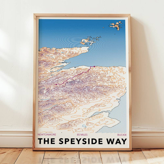 Framed map poster of The Speyside Way on a wooden floor with a white wall background