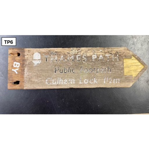 Wooden sign pointing to the Thames Path on a dark surface