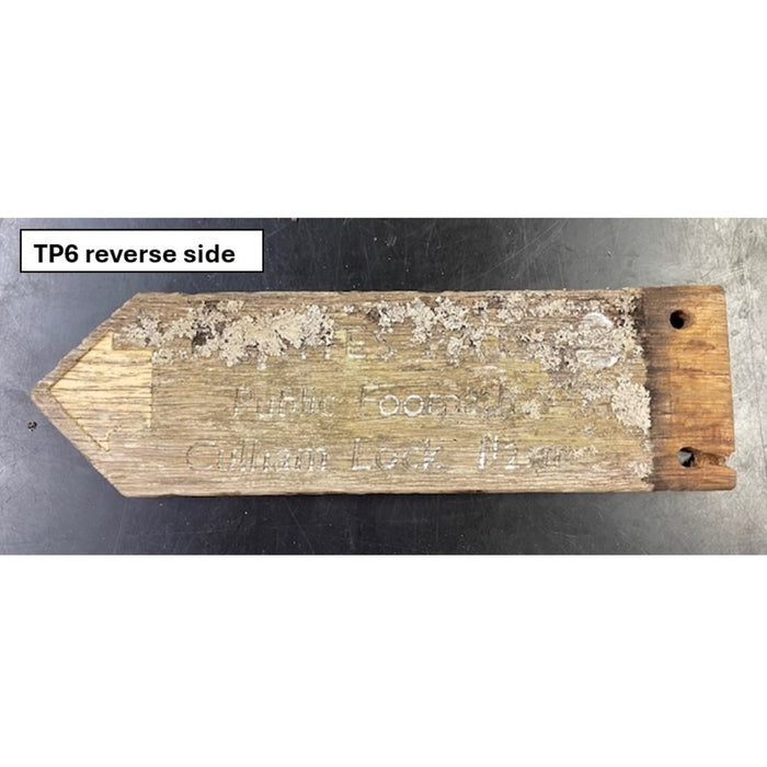 Wooden sign with engraved text on a metal surface, labeled 'TP6 reverse side'.